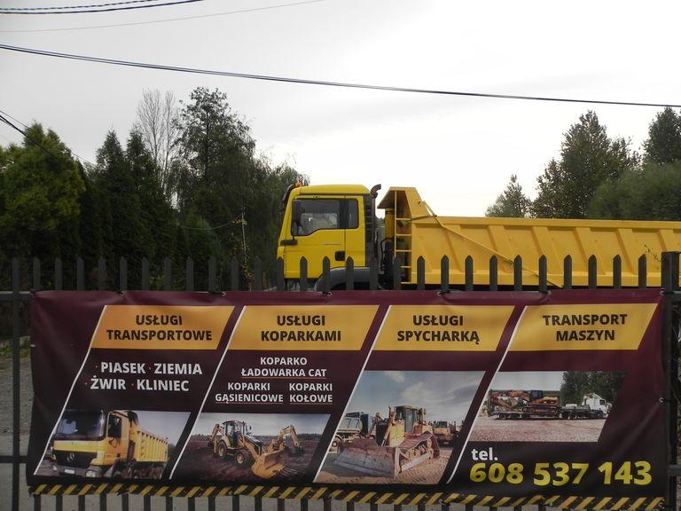 Reklama na płocie w tle żółta ciężarówka